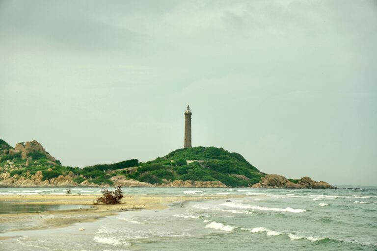 Peaceful coastal scene featuring a historic lighthouse on a lush island.