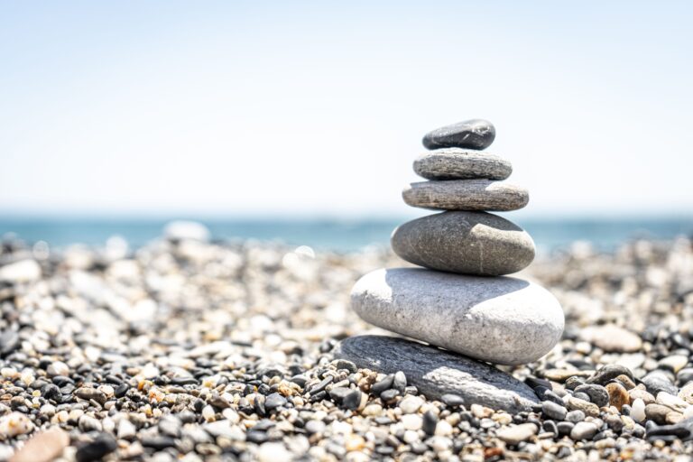 Peaceful stacked stones on a sunny pebble beach, symbolizing balance and tranquility.